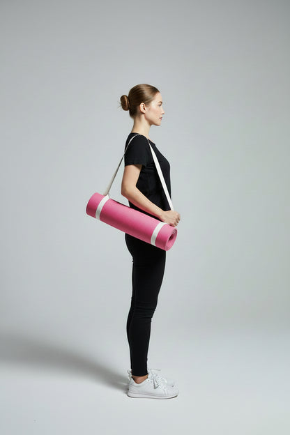 Woman holding a pink yoga mat with a strap against a gray background